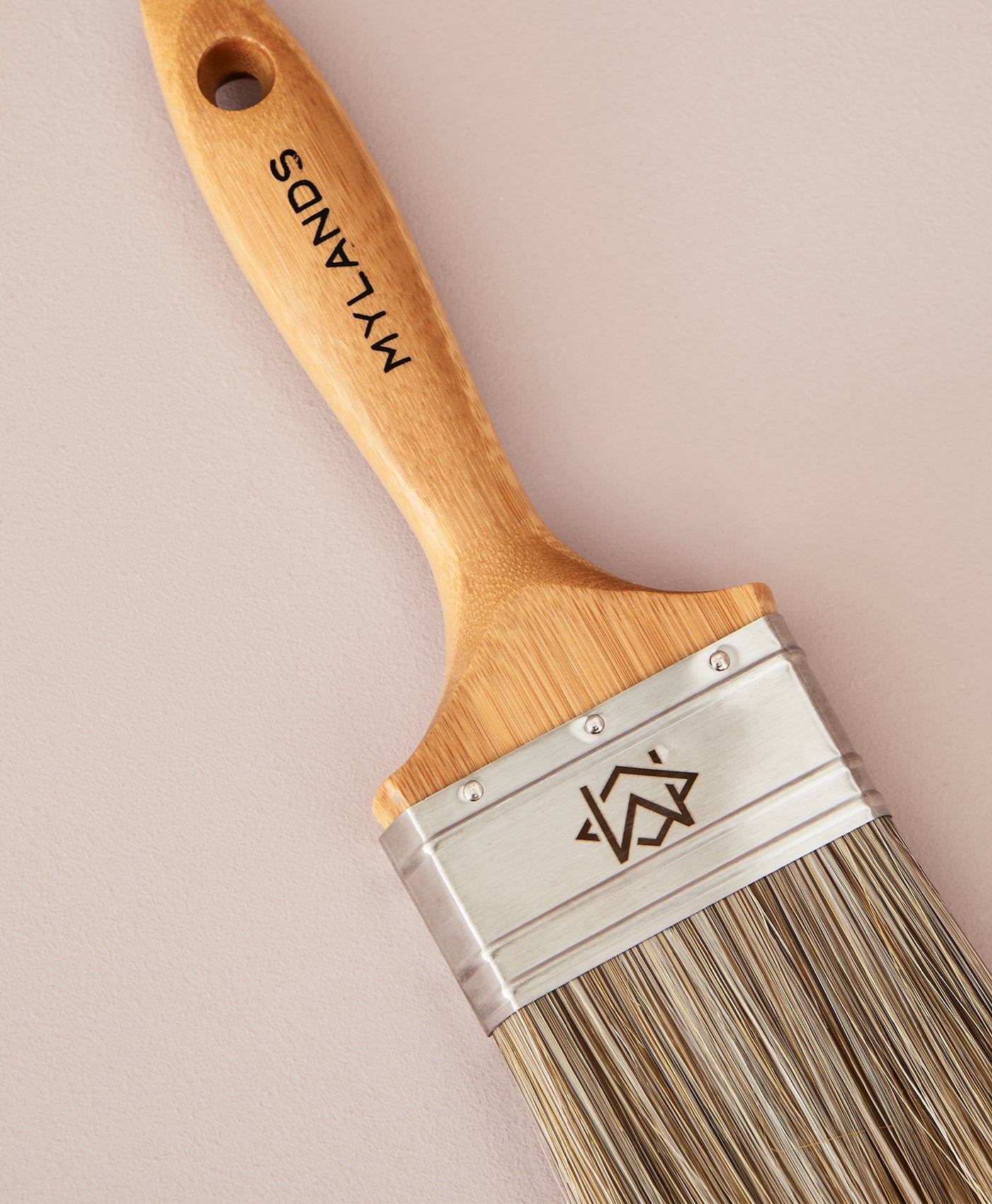 Mylands paint brush with wooden handle and metal ferrule on a beige background