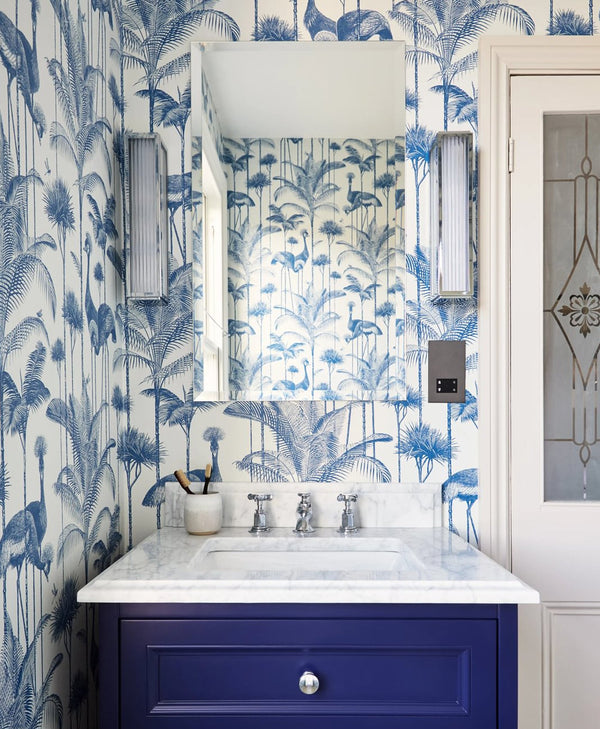 Bathroom with blue and white floral wallpaper, a dark blue cabinet, and a mirror.