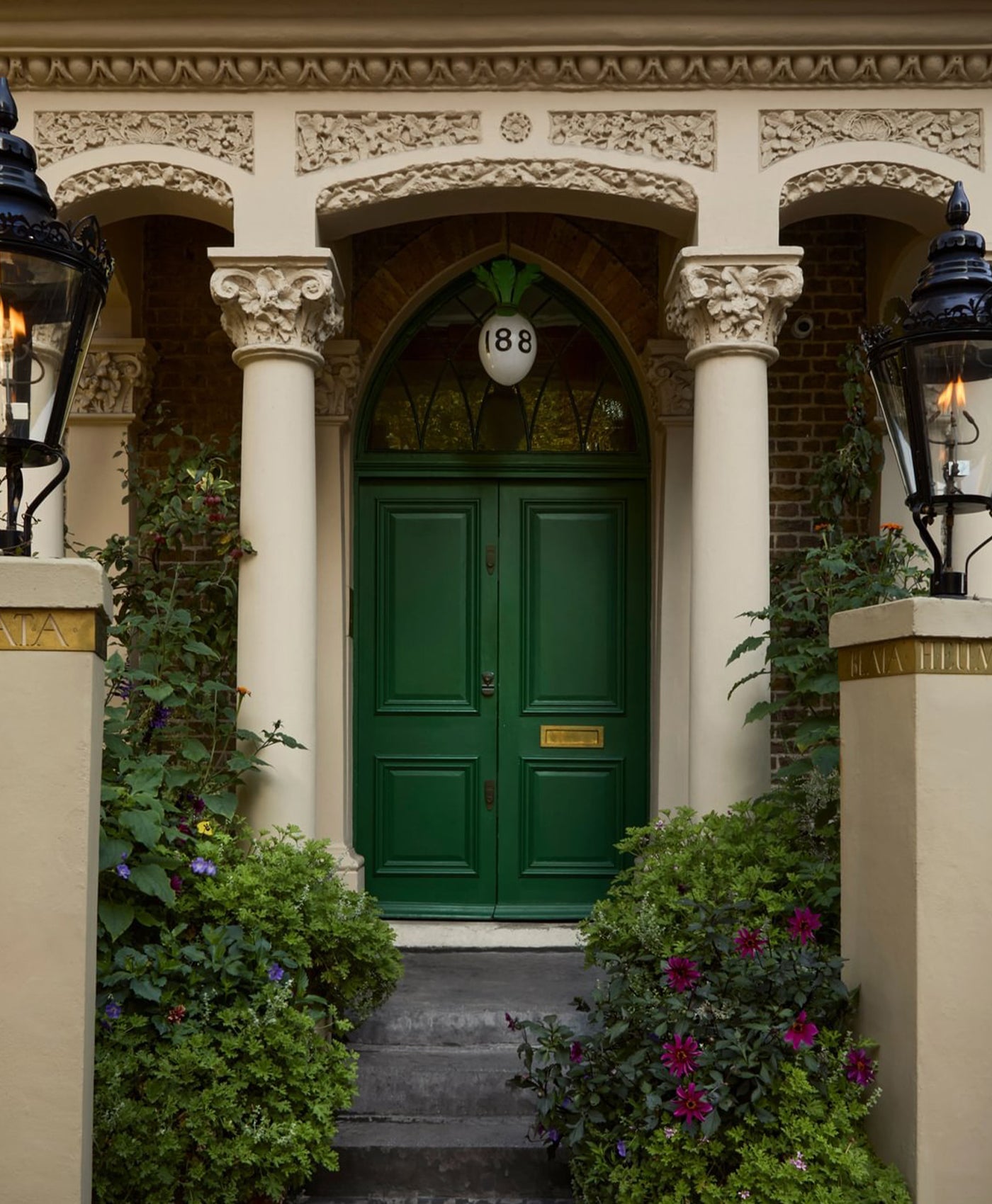 Green exterior door with decorative columns and ornate details on a building facade.