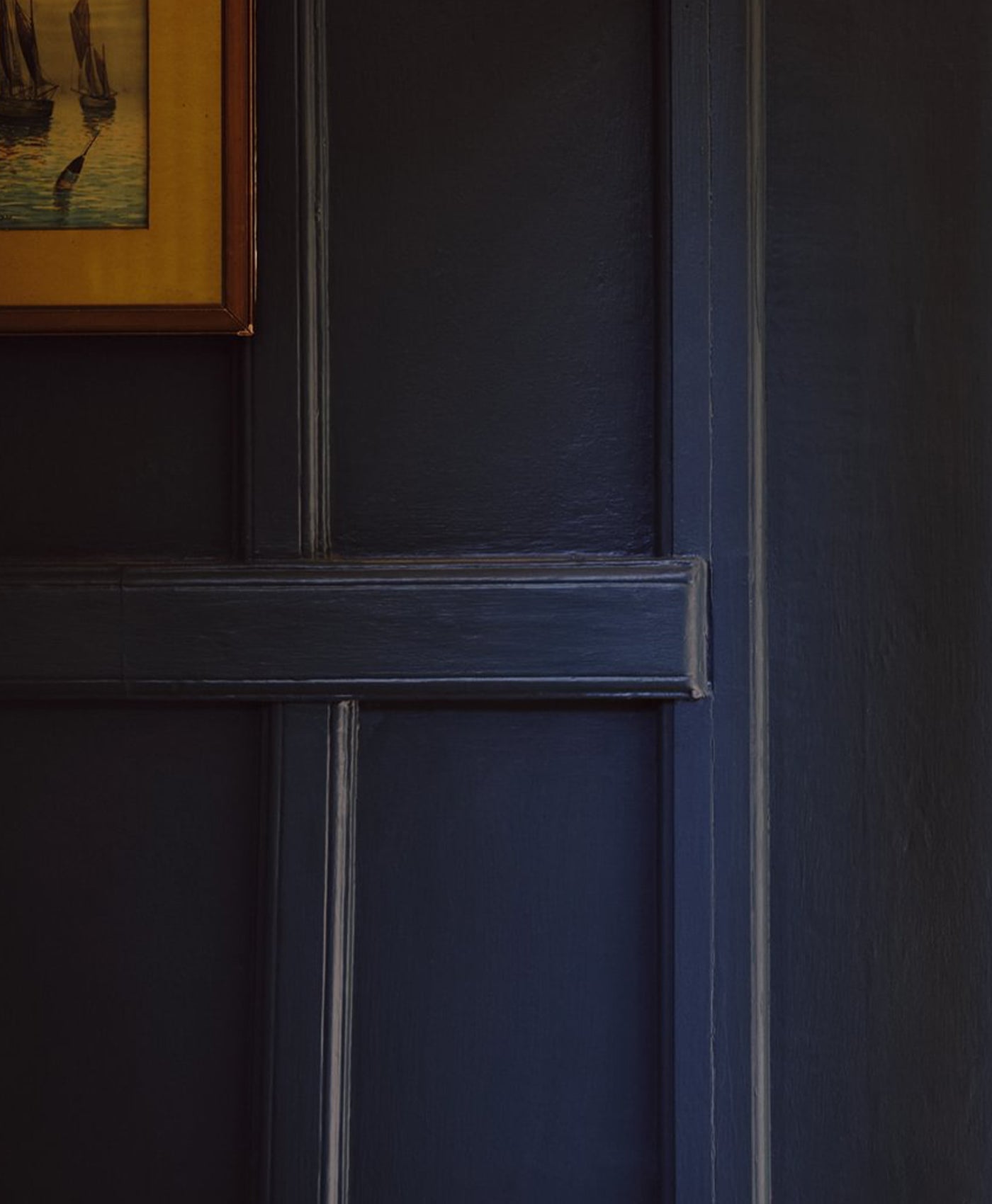 Dark blue panel with a framed painting in the corner
