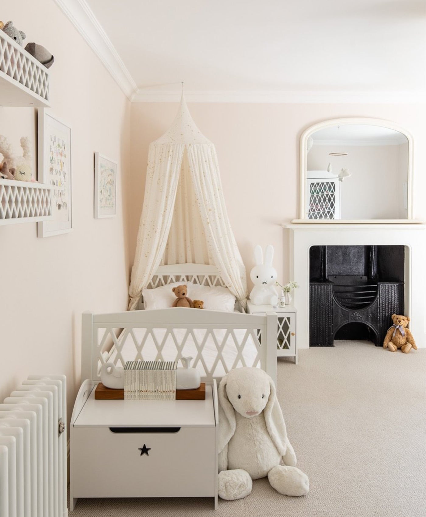 Pale pink nursery room with a crib, teddy bear, and decorative elements.
