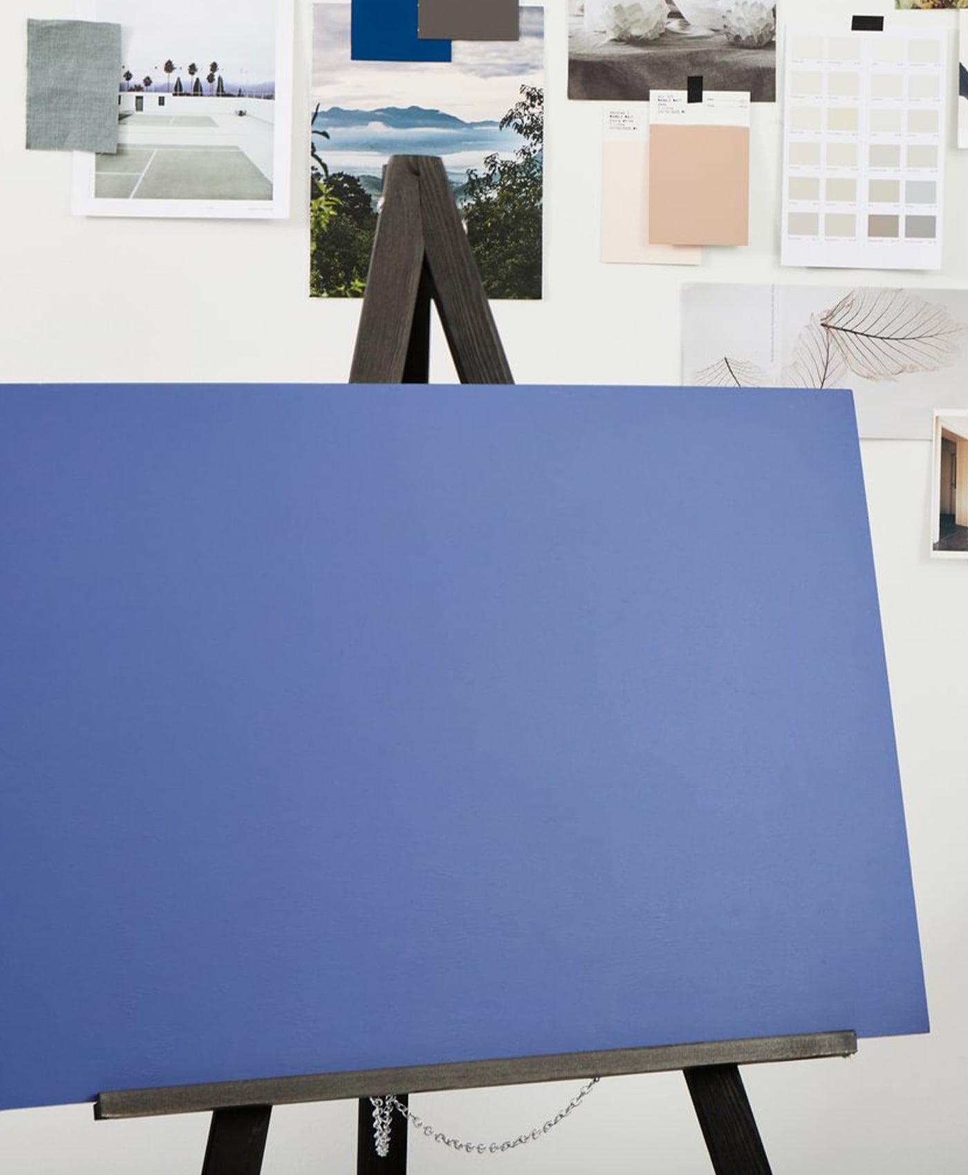 Blue canvas on an easel with a white wall featuring color swatches in the background