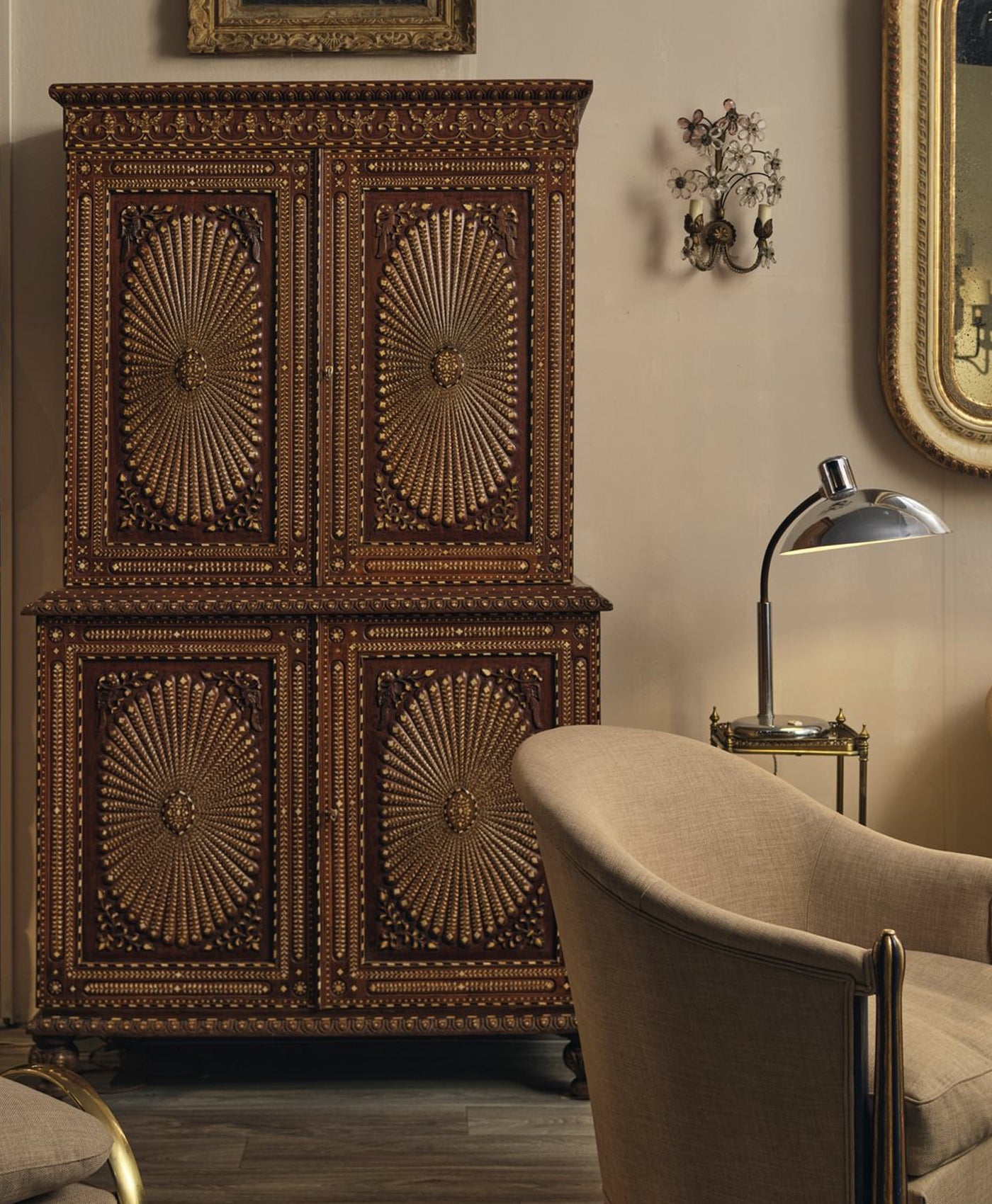 Decorative wooden cabinet with intricate carvings in a room with a lamp and chair. In warm neutral room.