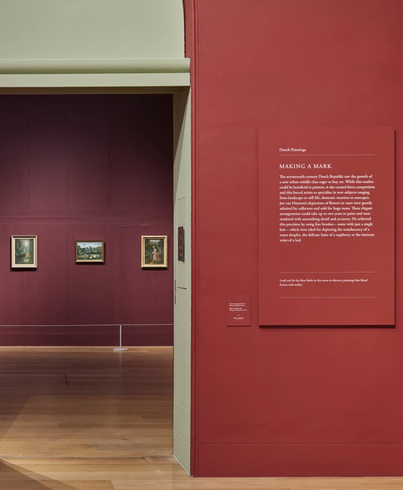 Dulwich Picture gallery with paintings on purple and red walls and an informational panel.