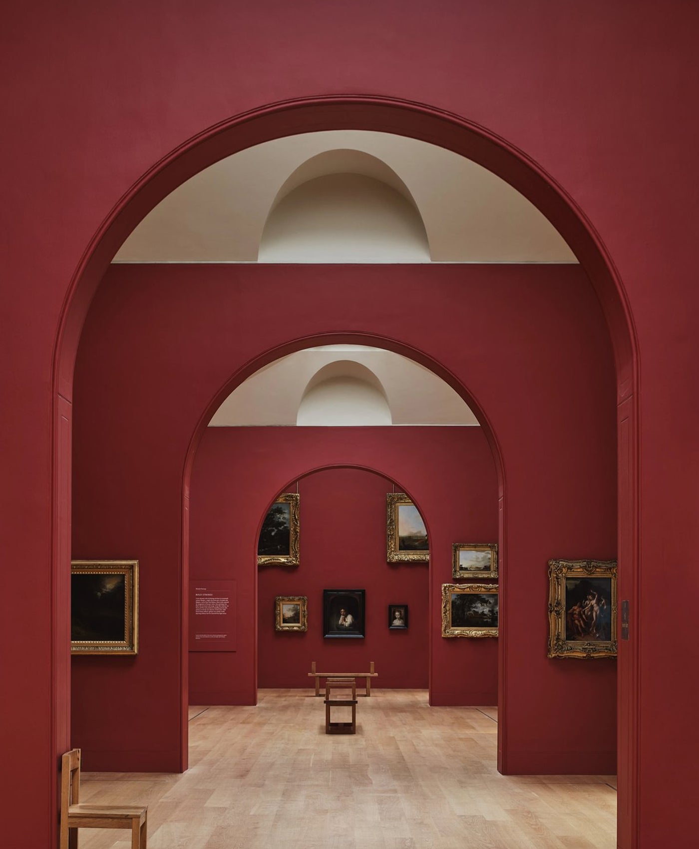 Dulwich Art gallery with red walls and arched doorways displaying framed paintings.