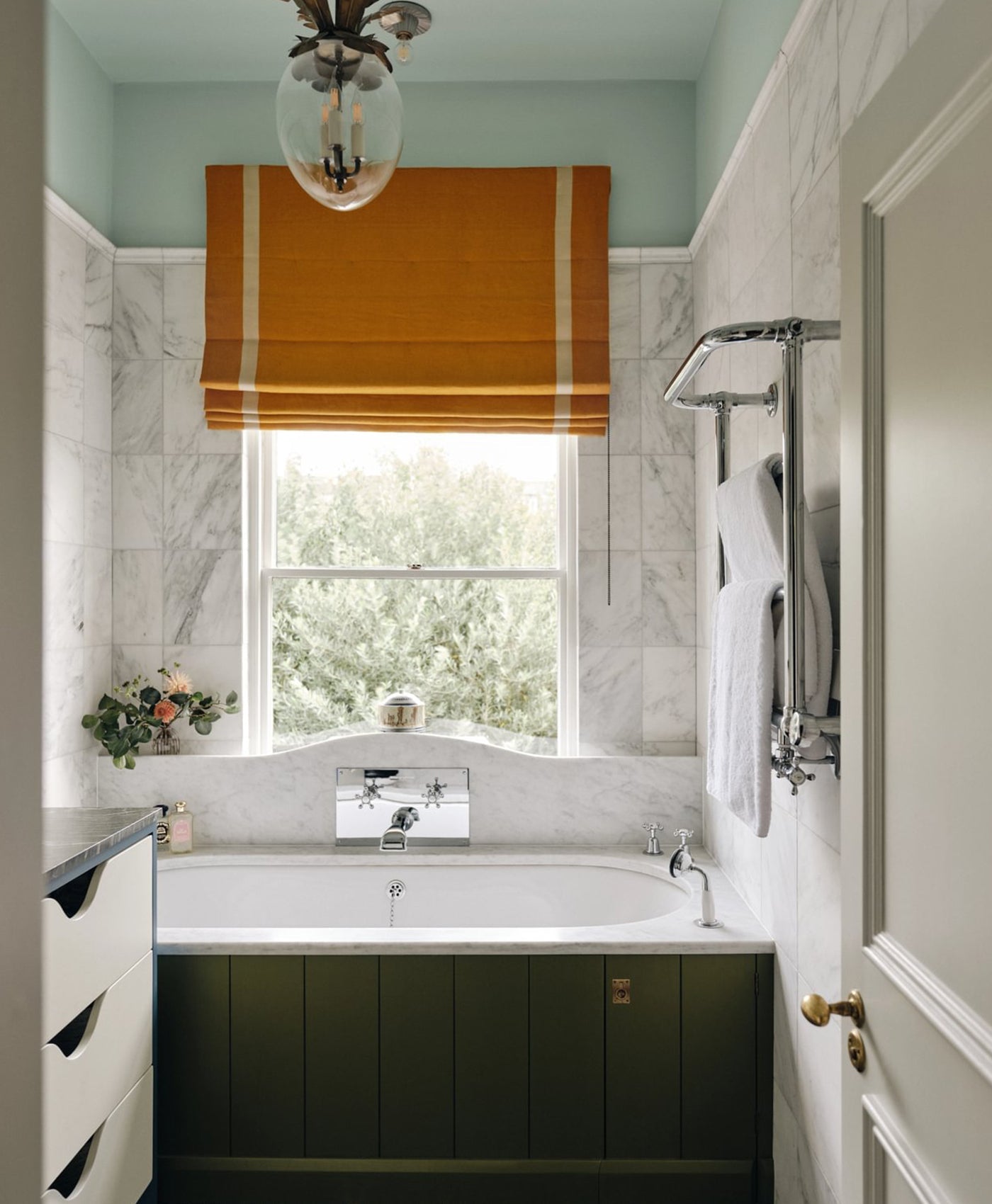 Bathroom with olive green bath panel, pale blue ceiling and ochre blind