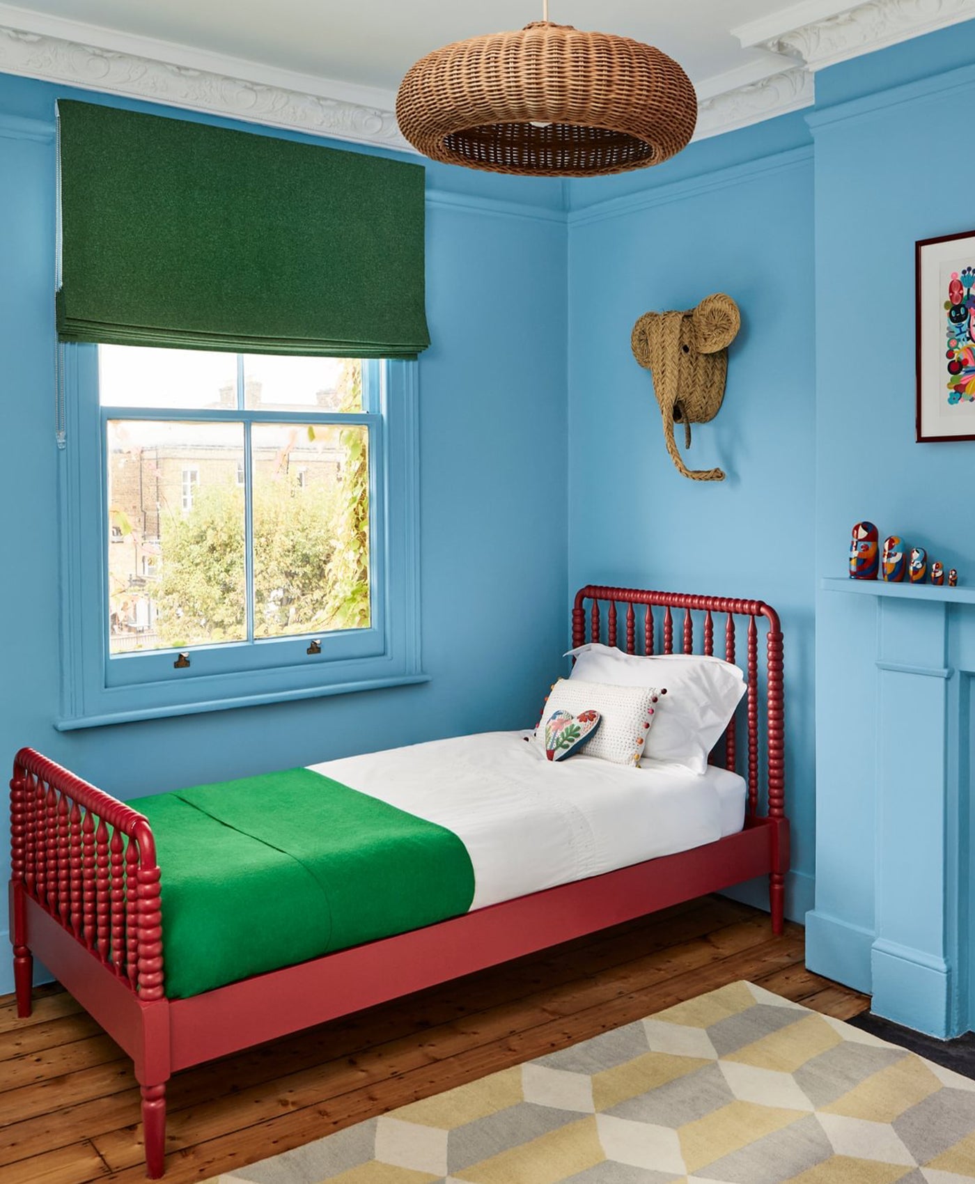 Children's bedroom with blue walls, red bed, and green accents.