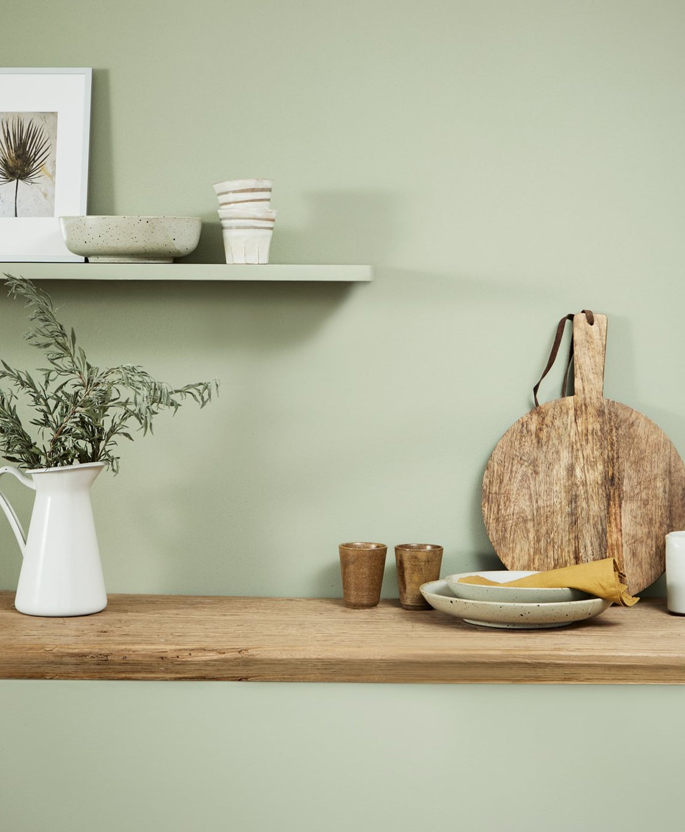 Wooden shelf with kitchen items against a soft green wall
