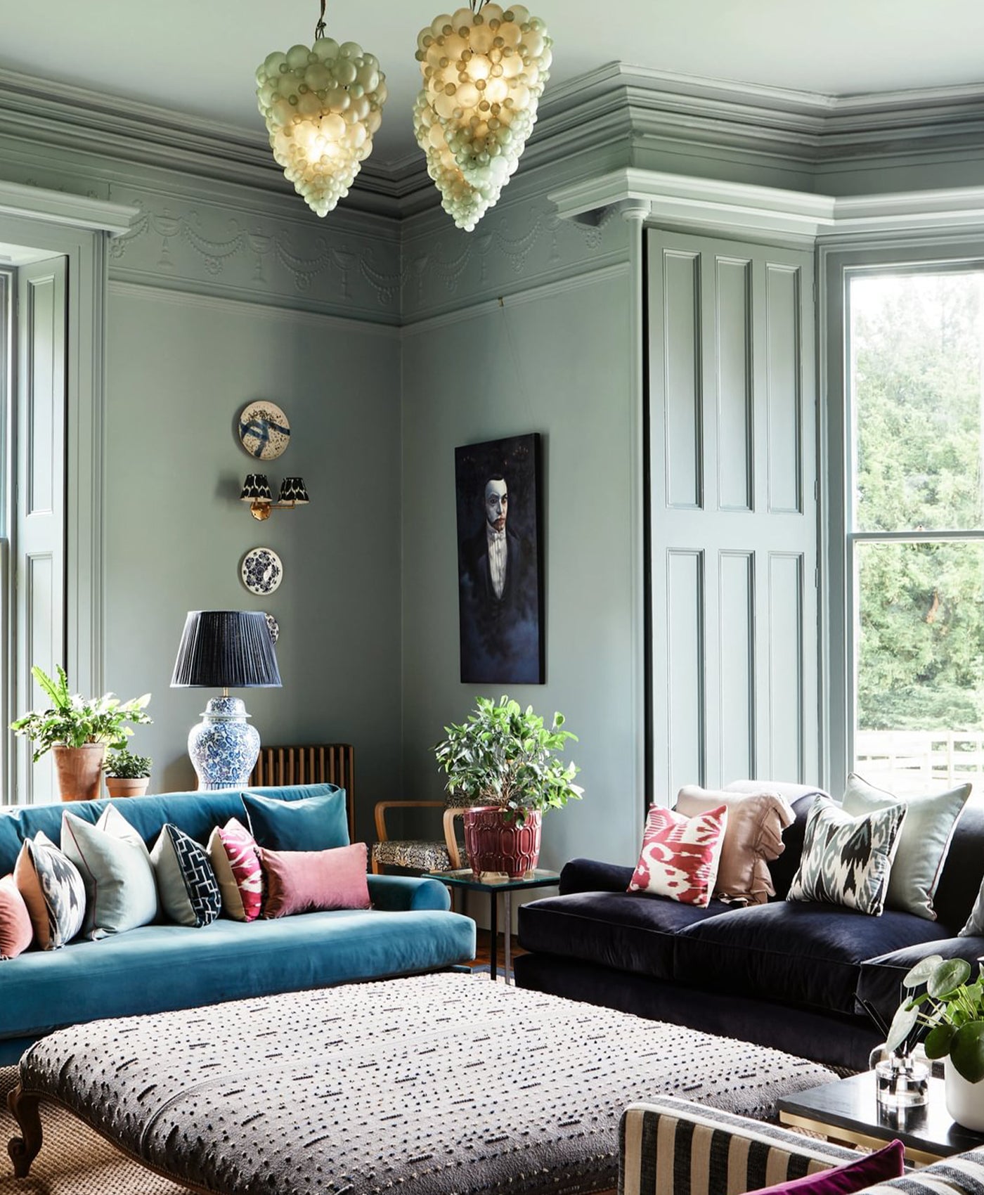 green blue living room with blue sofa, ottoman, and decorative pillows.