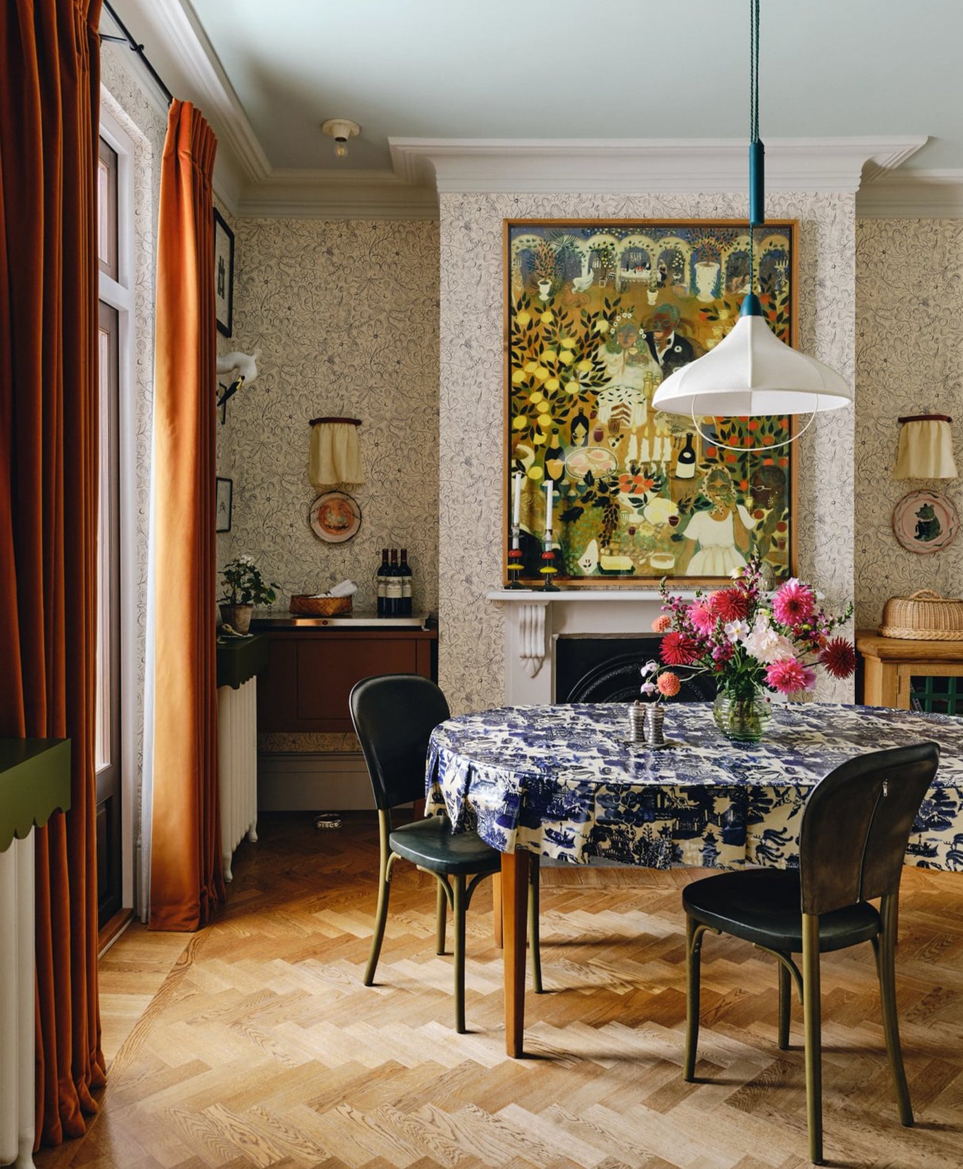 Dining room patterned wallpaper, orange curtains, slight blue ceiling and off-white wooden trims