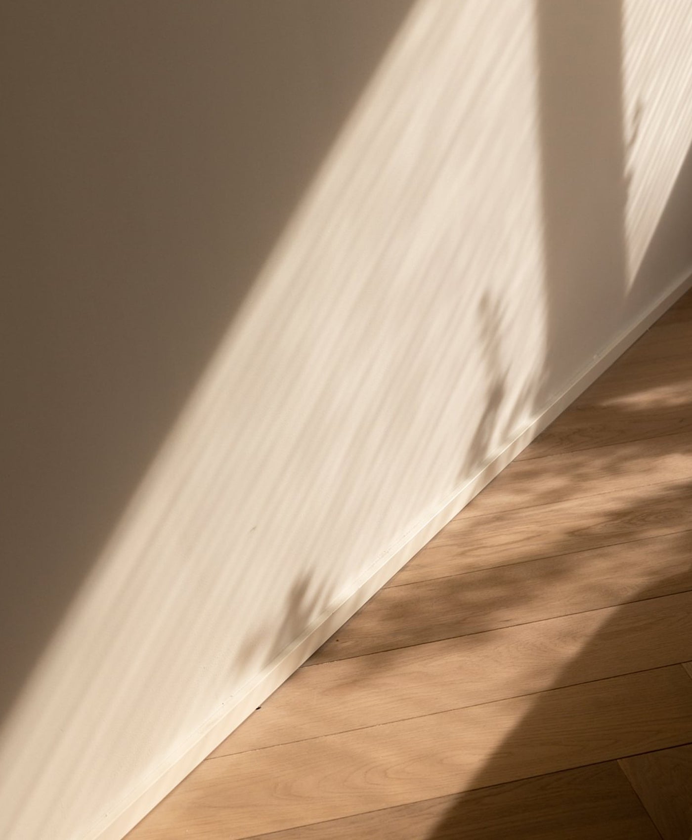 Light brown wooden floor with a neutral stone wall casting shadows