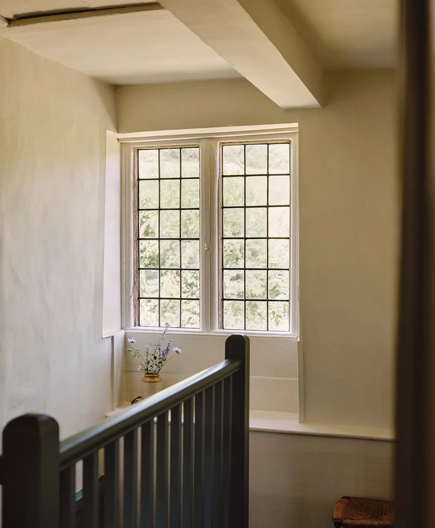 Hallway in warm neutral tone with a large window and blue-green bannister
