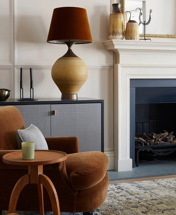 Cosy neutral living room with brown armchair, lamp, and fireplace.