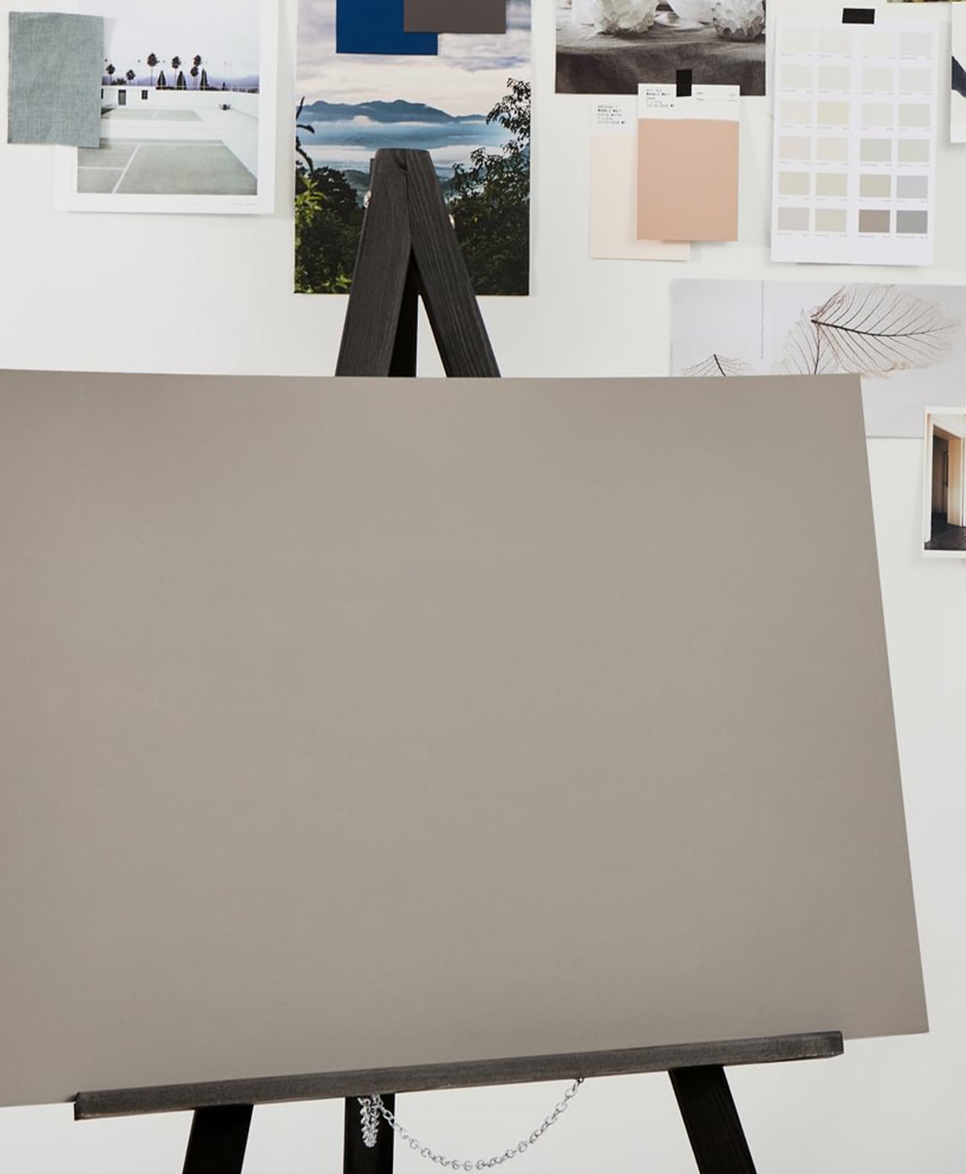 Gray canvas on an easel with color swatches and images in the background