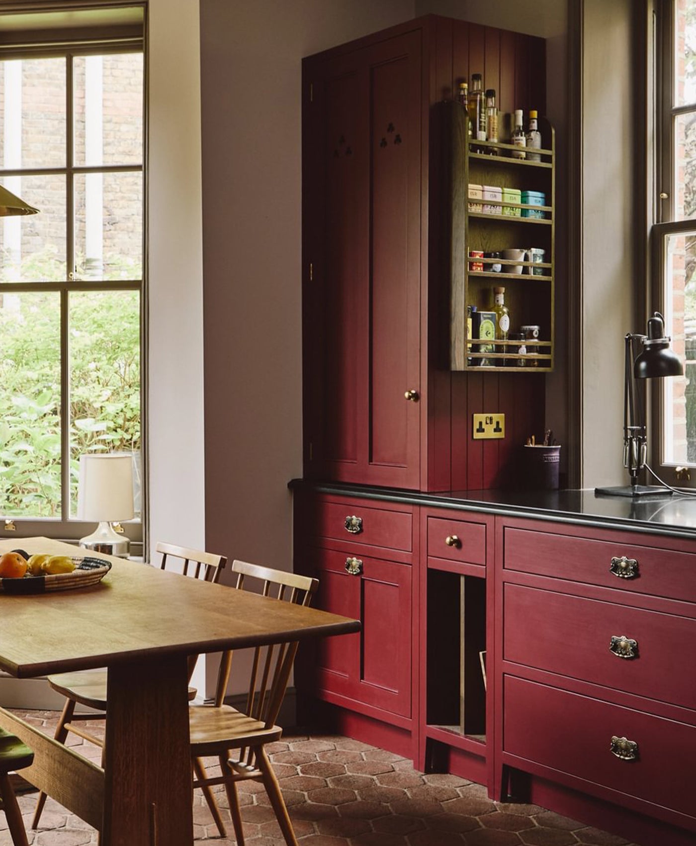 Kitchen with crimson red cabinets, wooden table, and chairs.