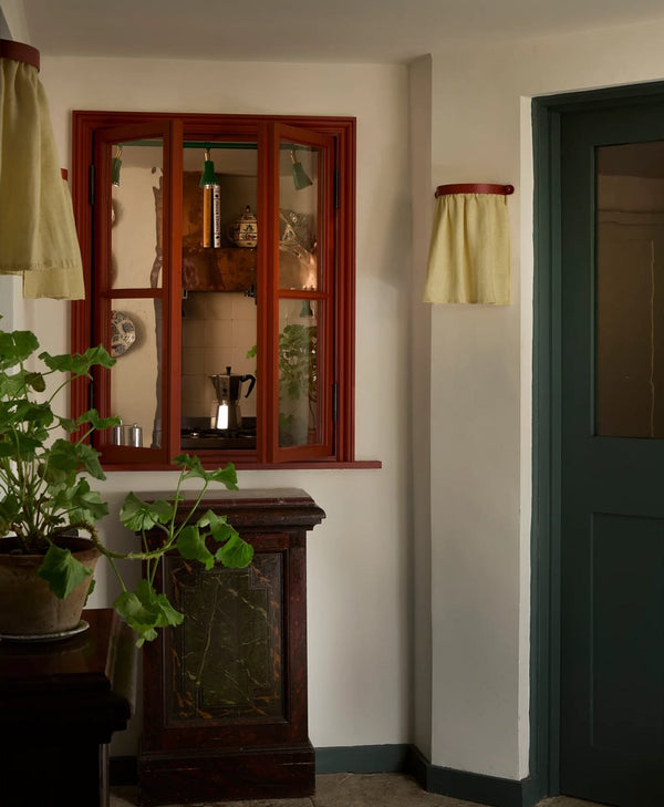 Vintage-style room with red painted window frame, blue-green painted door and arm white walls