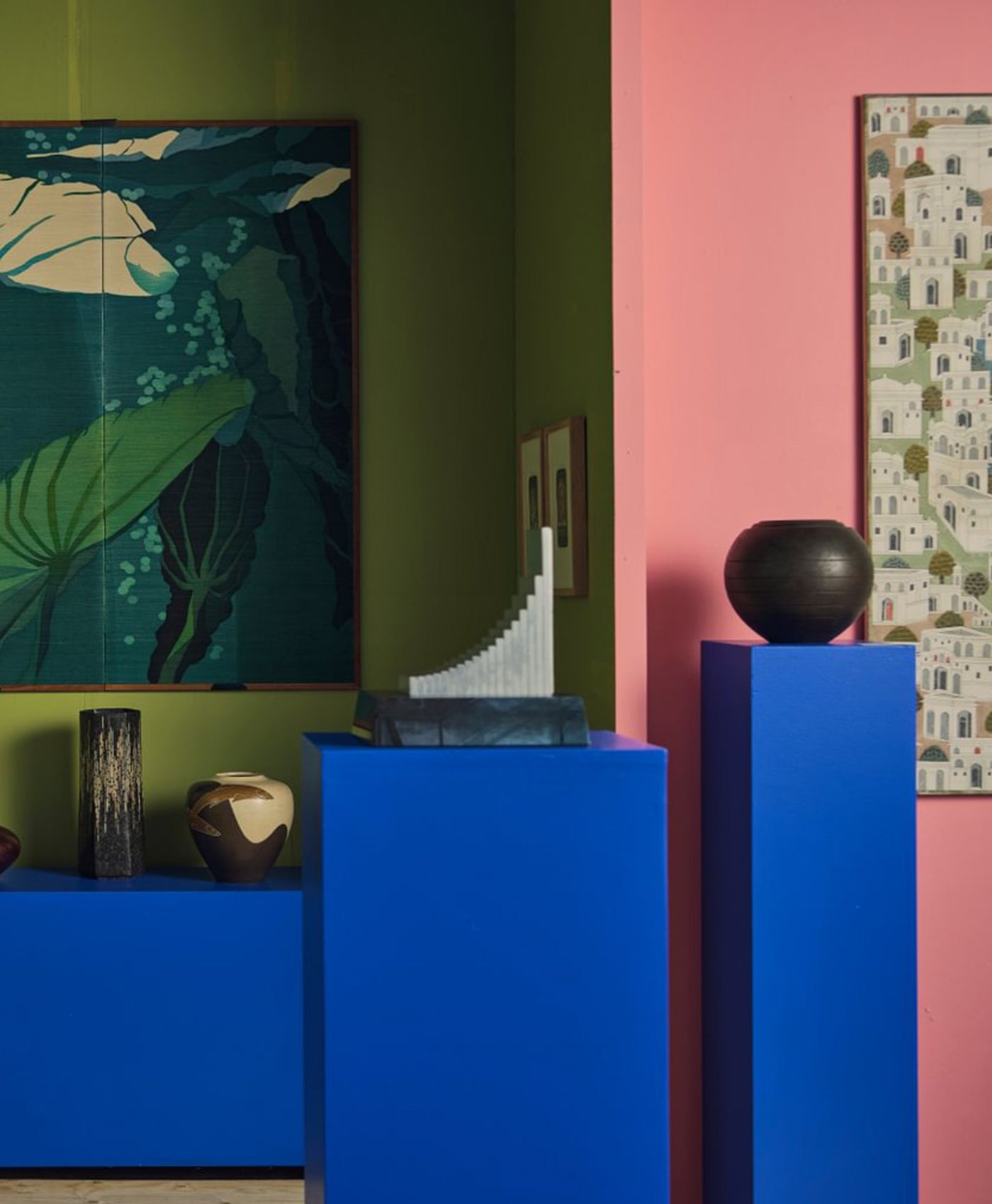Colorful room interior with green wall, pink wall, blue furniture, and decorative items.