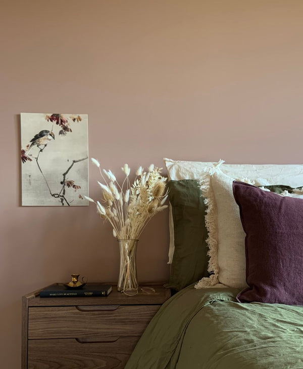 Bedroom in plaster coloured paint with a bed, nightstand, and wall art