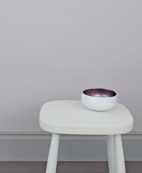 White stool with a purple bowl on a neutral grey background