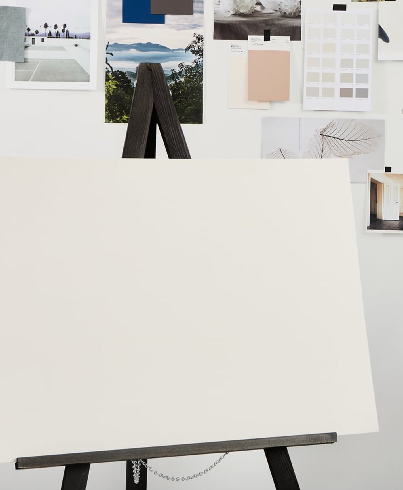 White canvas on a black easel with color swatches and images in the background