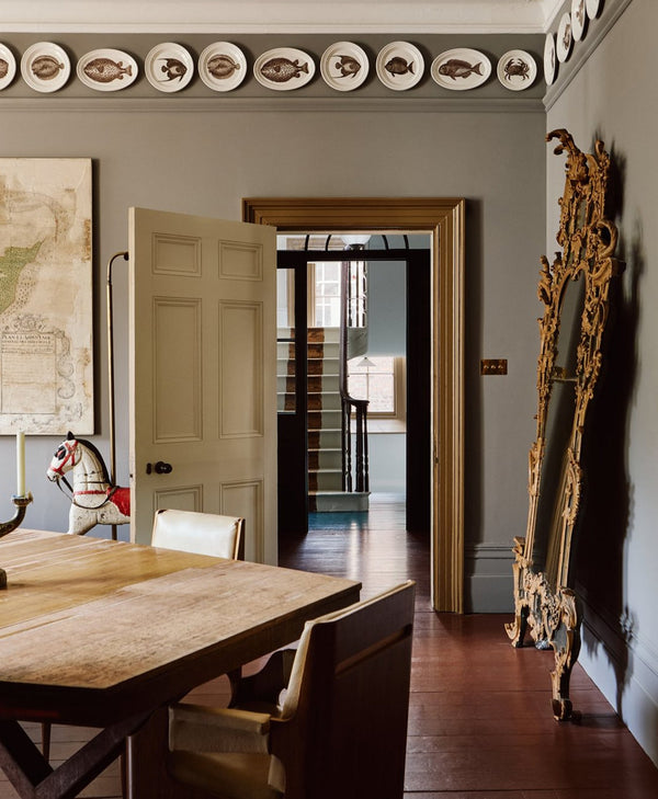 mid grey dining room with wooden table, chairs, and decorative wall plates.