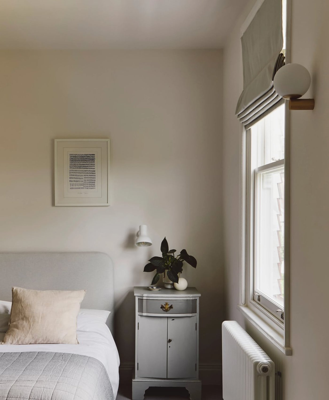 Cosy cool white bedroom with a bed, nightstand, and window.