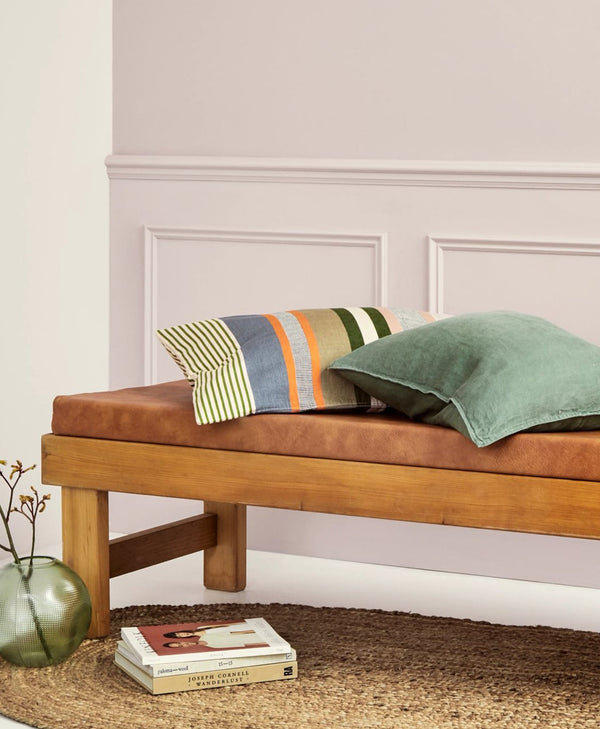 Wooden bench with cushions against a traditional white wall