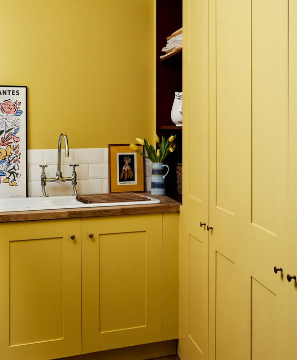 Mustard yellow kitchen with sink, cabinets, and decorative elements.