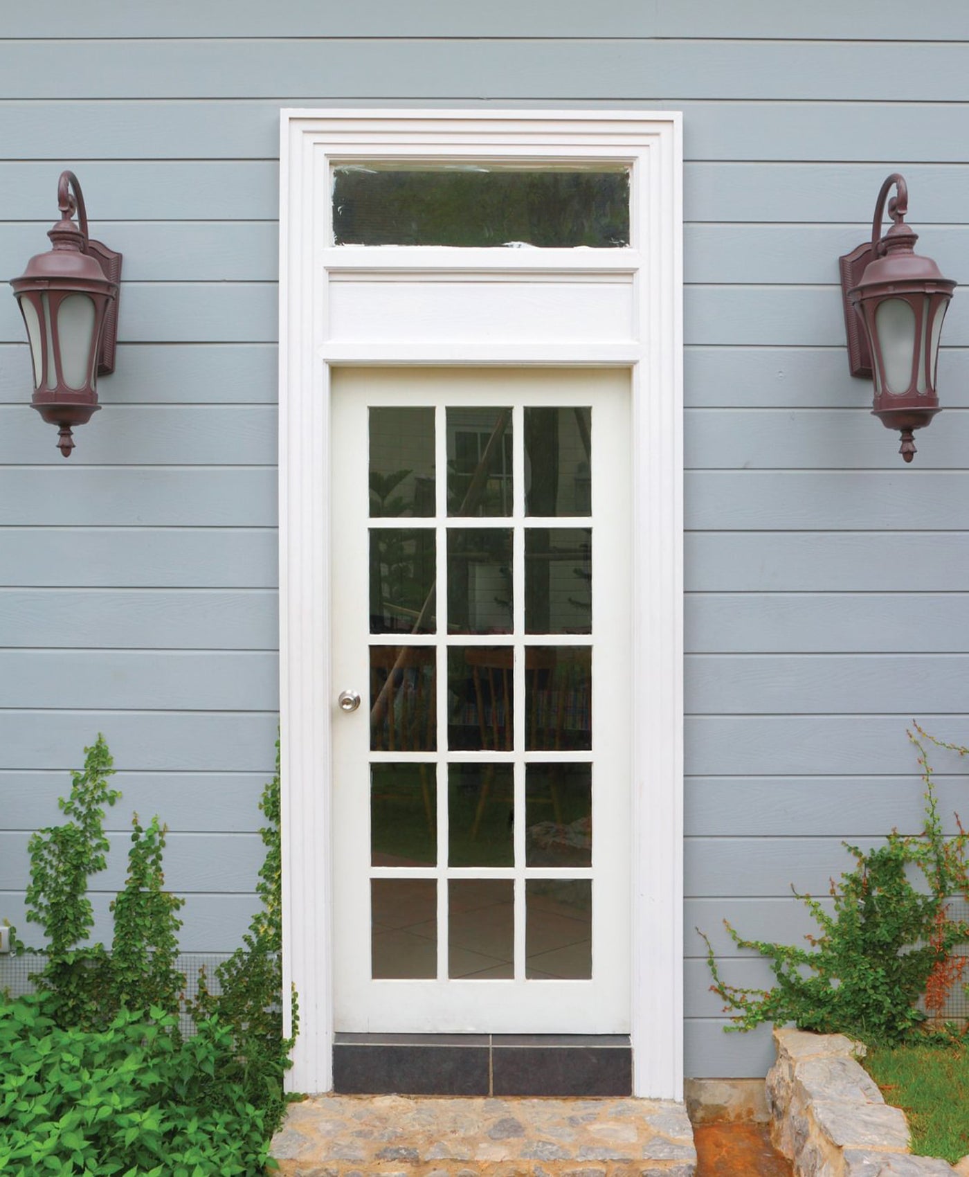 White door with glass panels on a blue grey house exterior