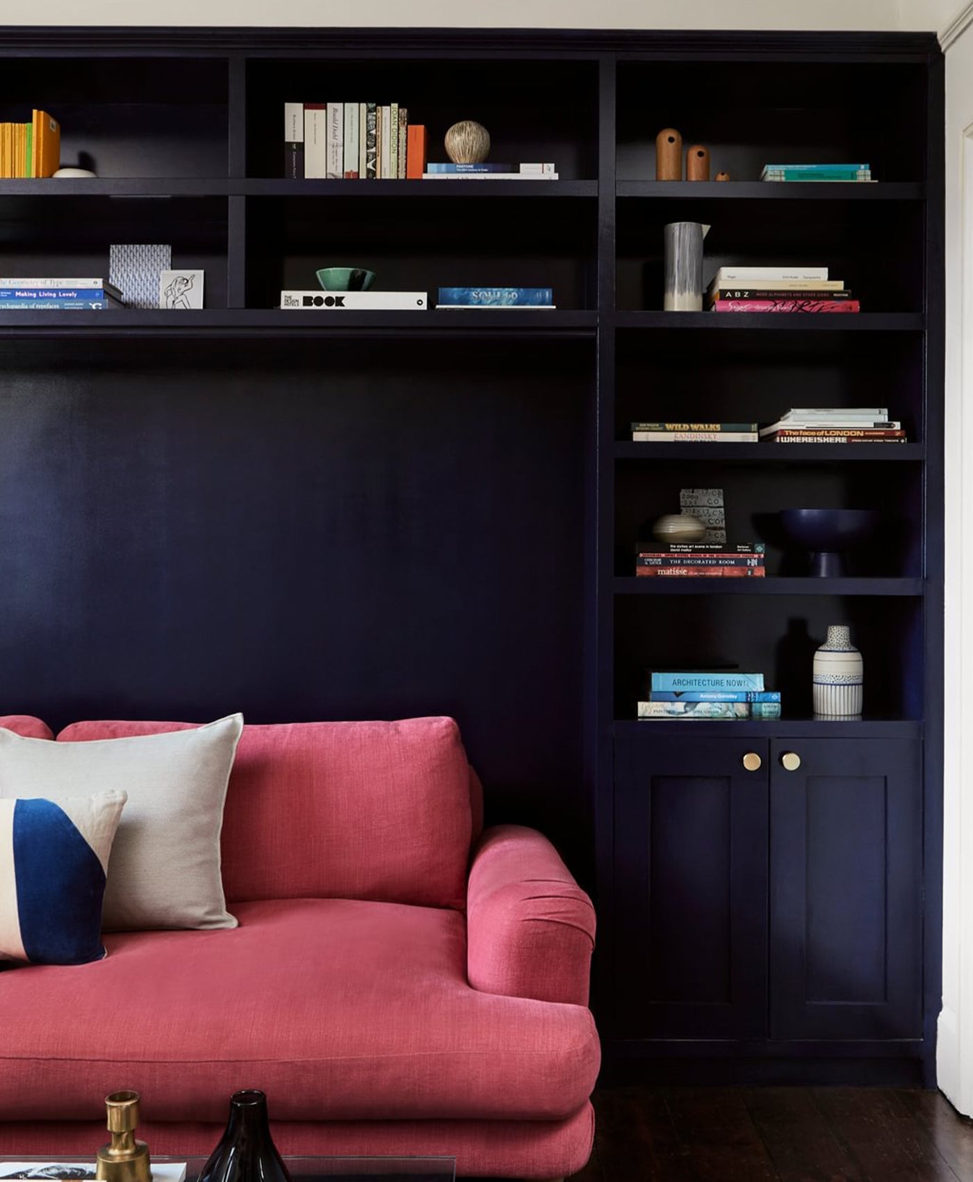 Pink sofa in front of a dark blue bookshelf with decorative items