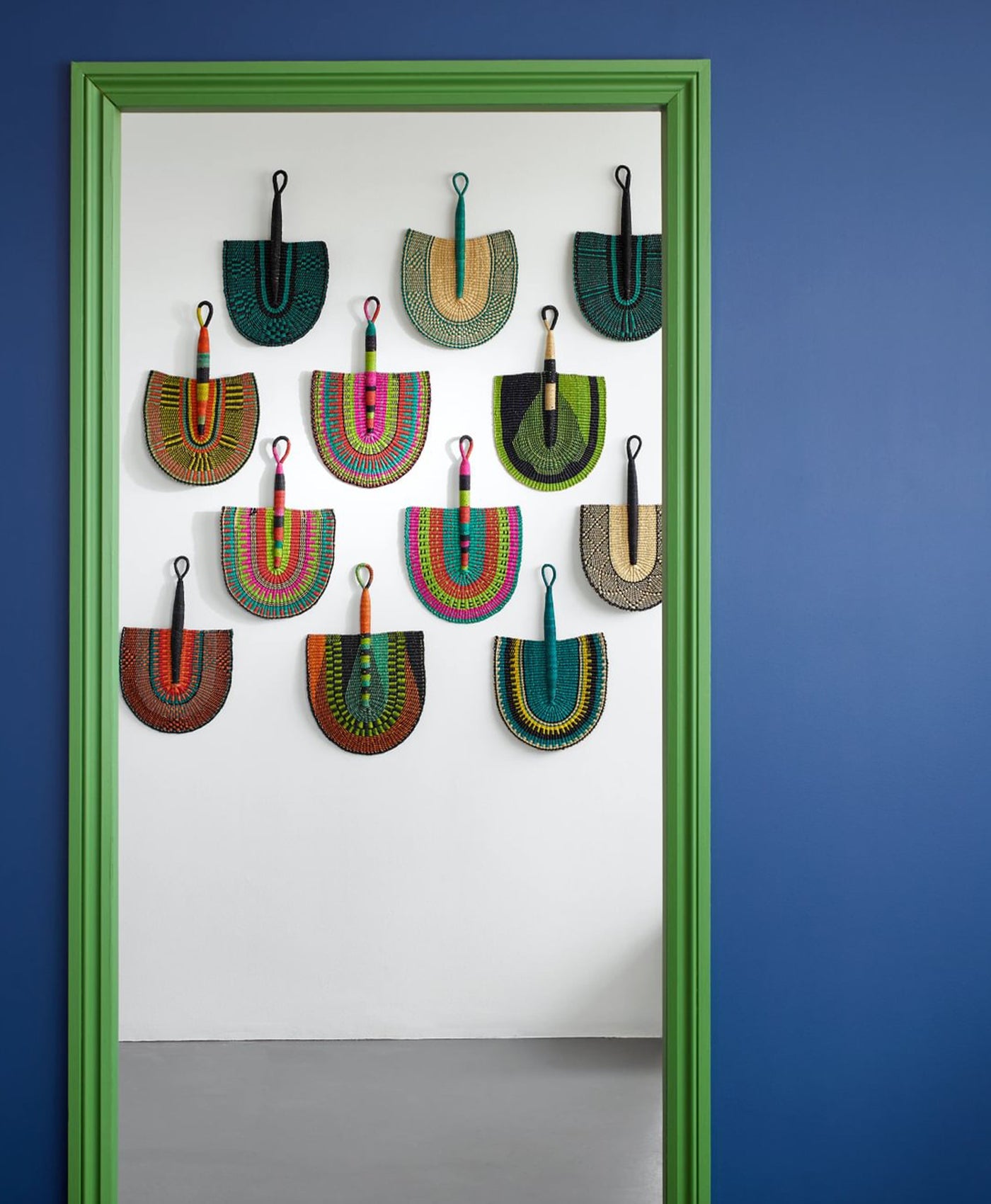 Colorful handbags hanging on a white door with a blue wall background