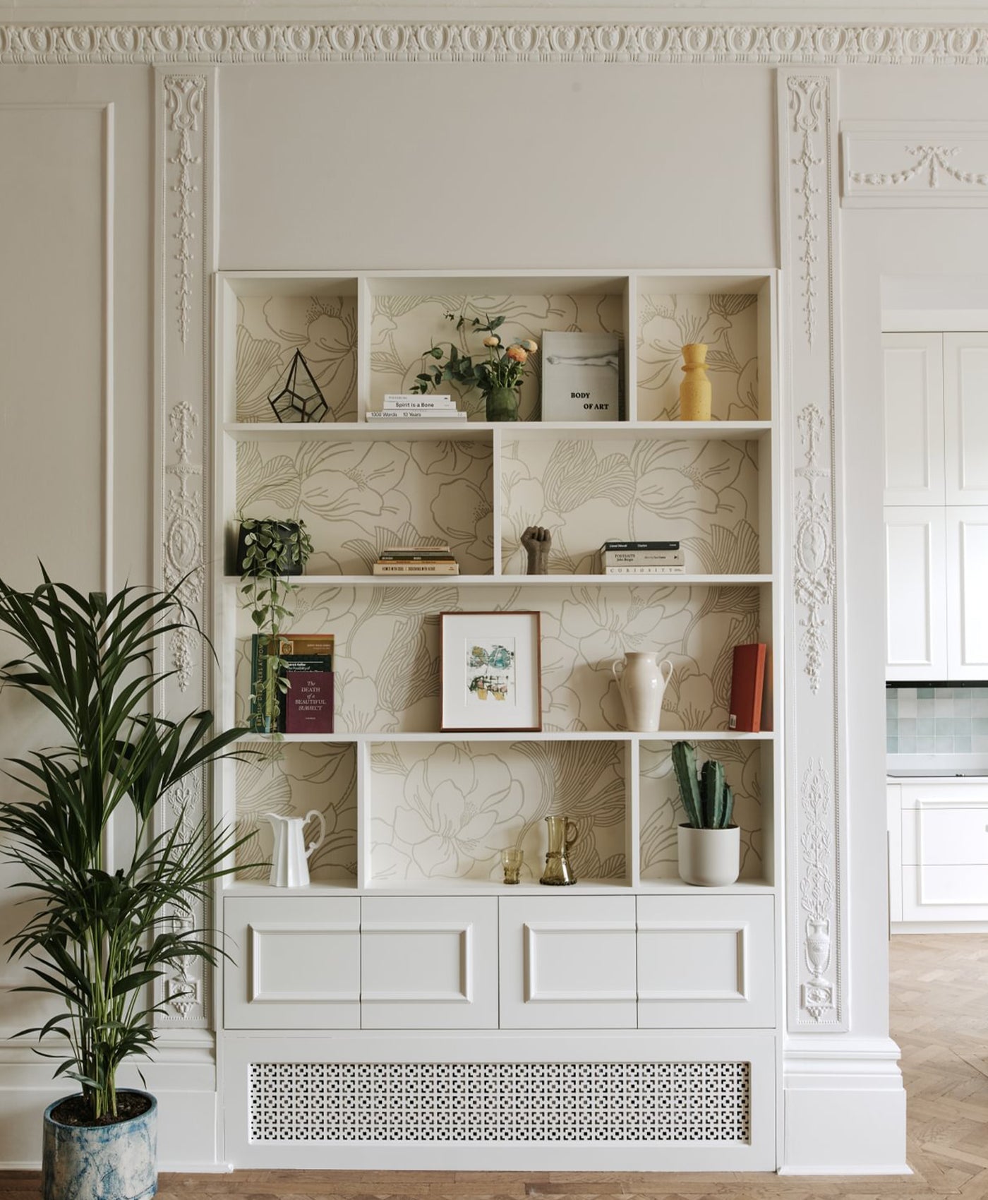 Off-white bookshelf with decorative items against a light wall