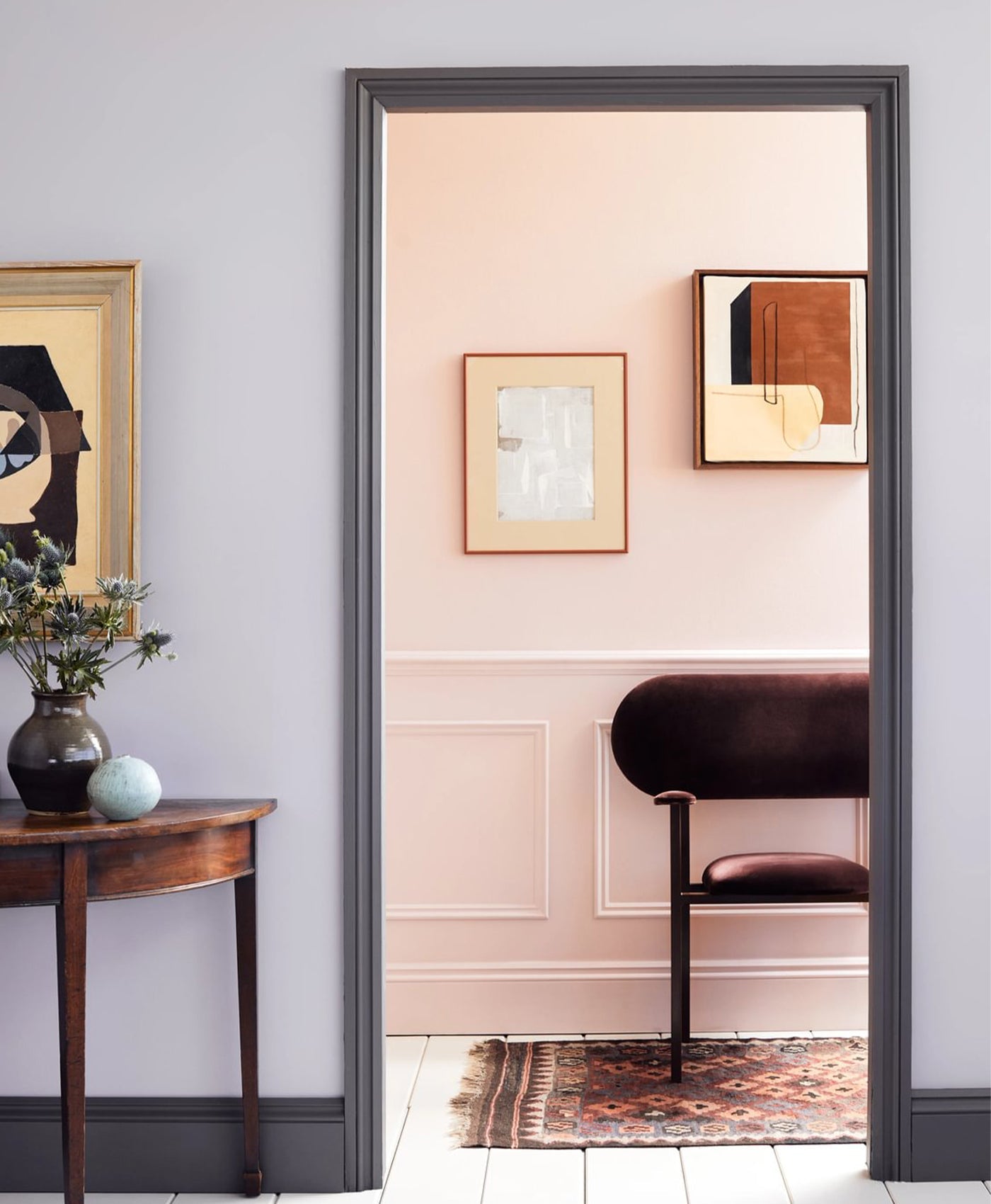 Lilac grey room with dark grey skirting leading to light pink room and wooden panelling and dark red velvet chair