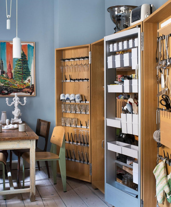 Classic blue kitchen with open wooden cabinet revealing storage compartments.