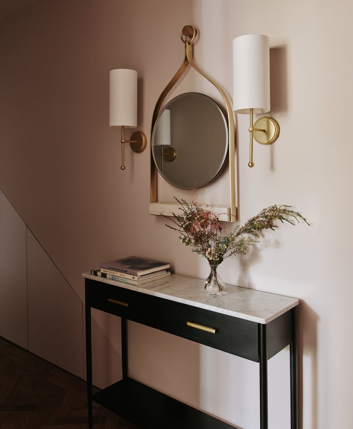 Console table with mirror and decorative items against a wall in white hallway setting