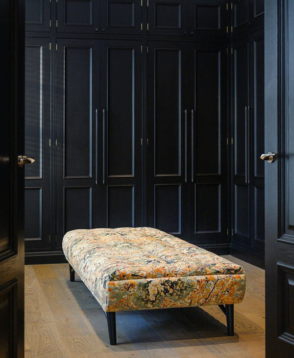 Patterned bench in a dressing room with black panelled wardrobe doors