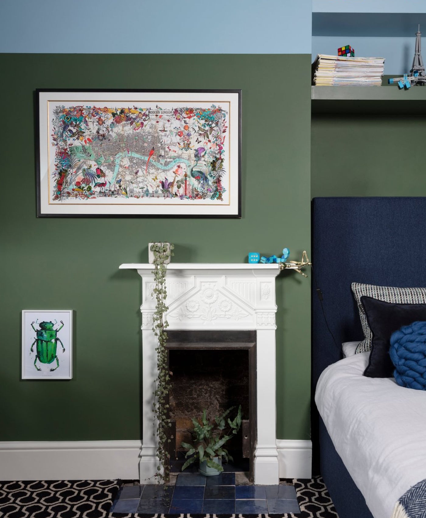 Decorative bedroom with deep green walls, a fireplace, and framed artwork.