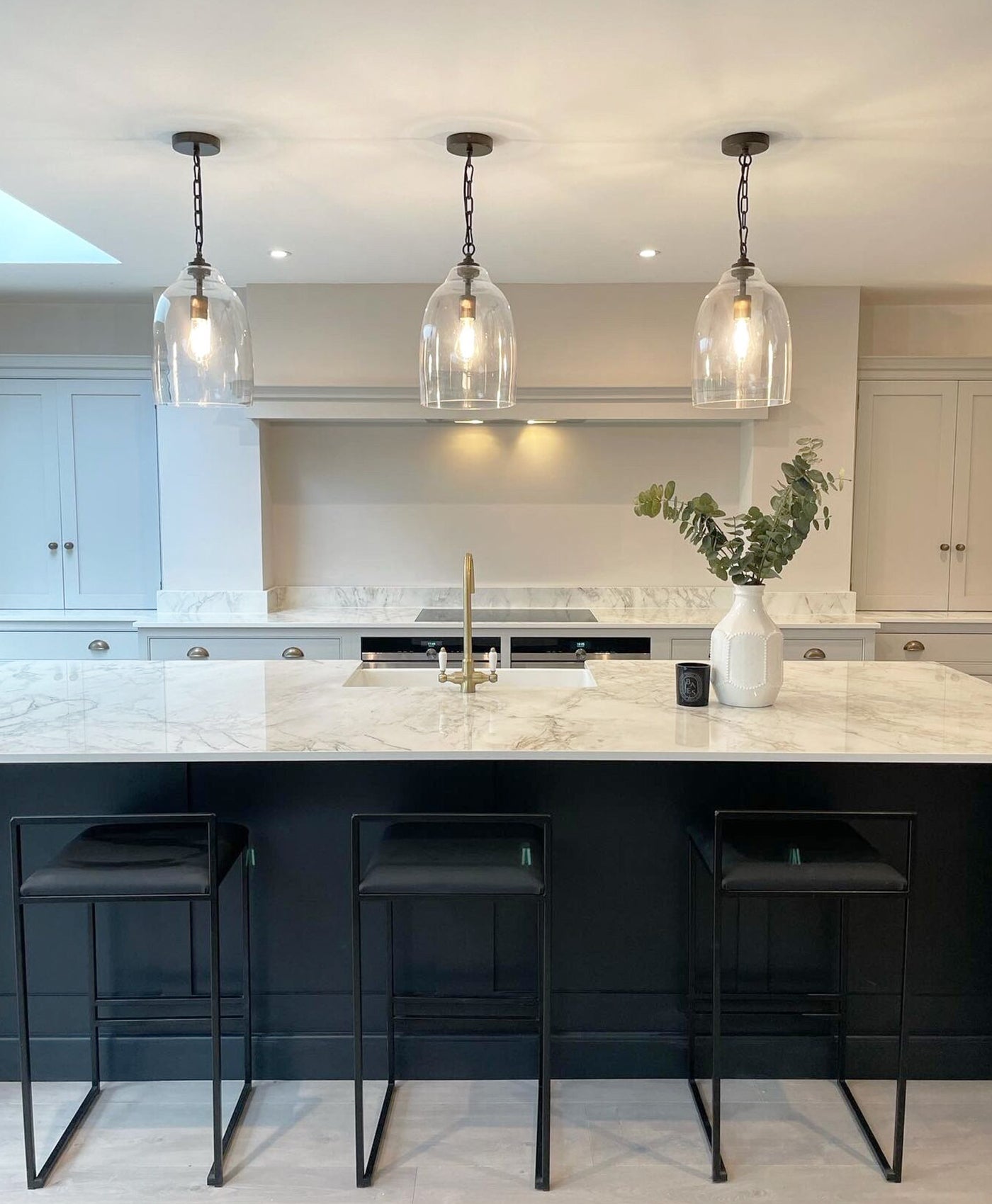 Modern kitchen with marble island top, dark charcoal island base, pendant lights, and bar stools.