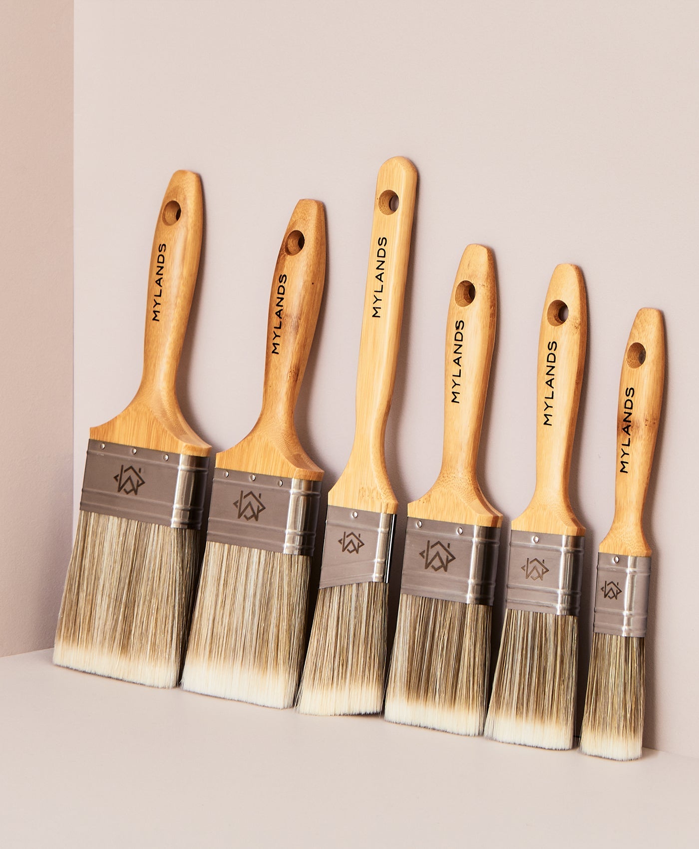 Set of five Mylands paint brushes with wooden handles and metal ferrules on a neutral background.