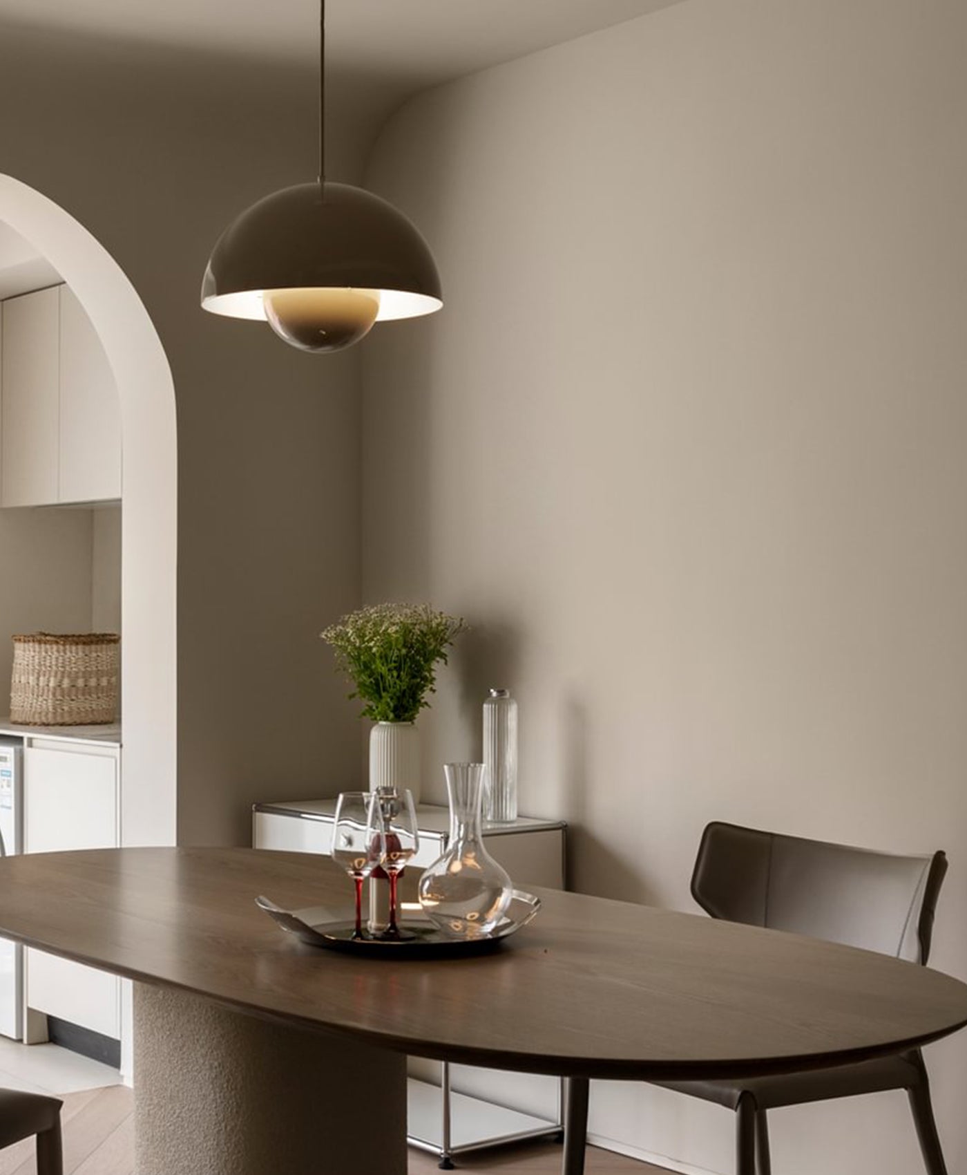 Stone coloured dining room with a table, chairs, and a pendant light fixture.