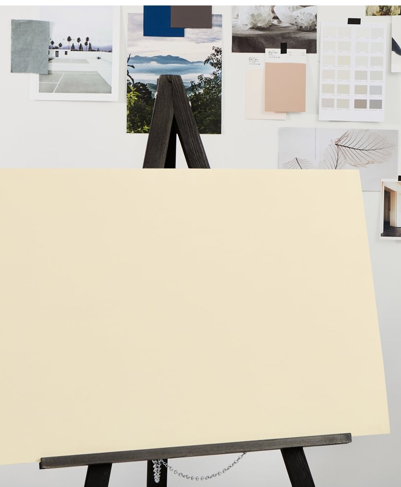 Beige canvas on an easel with a collage of images in the background