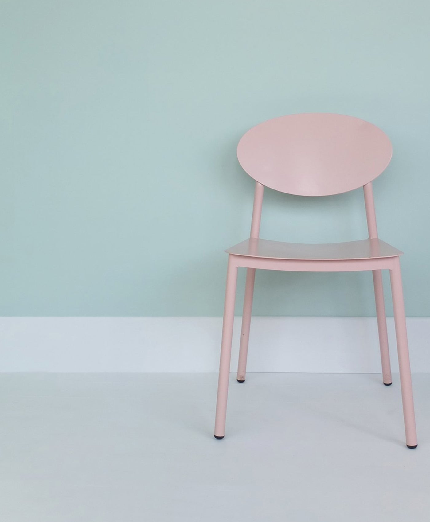 Pink chair against a light blue wall and white floor