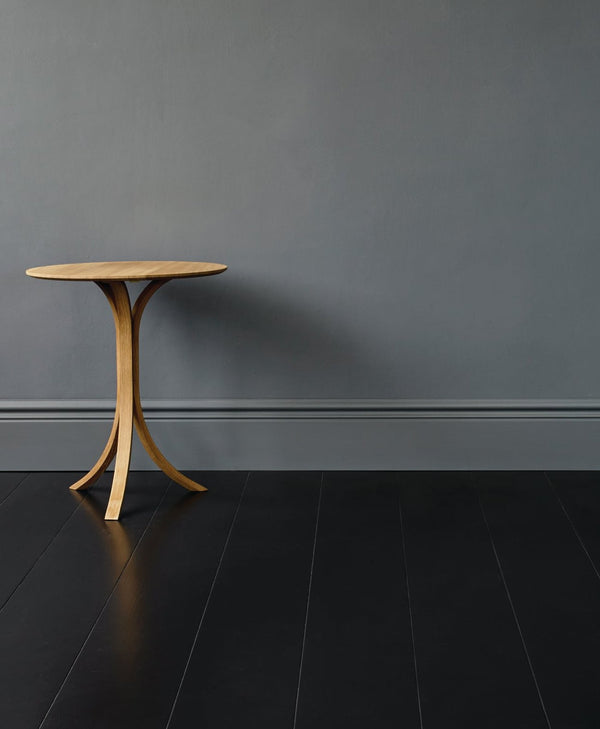 Wooden side table against a gray wall on a black floor
