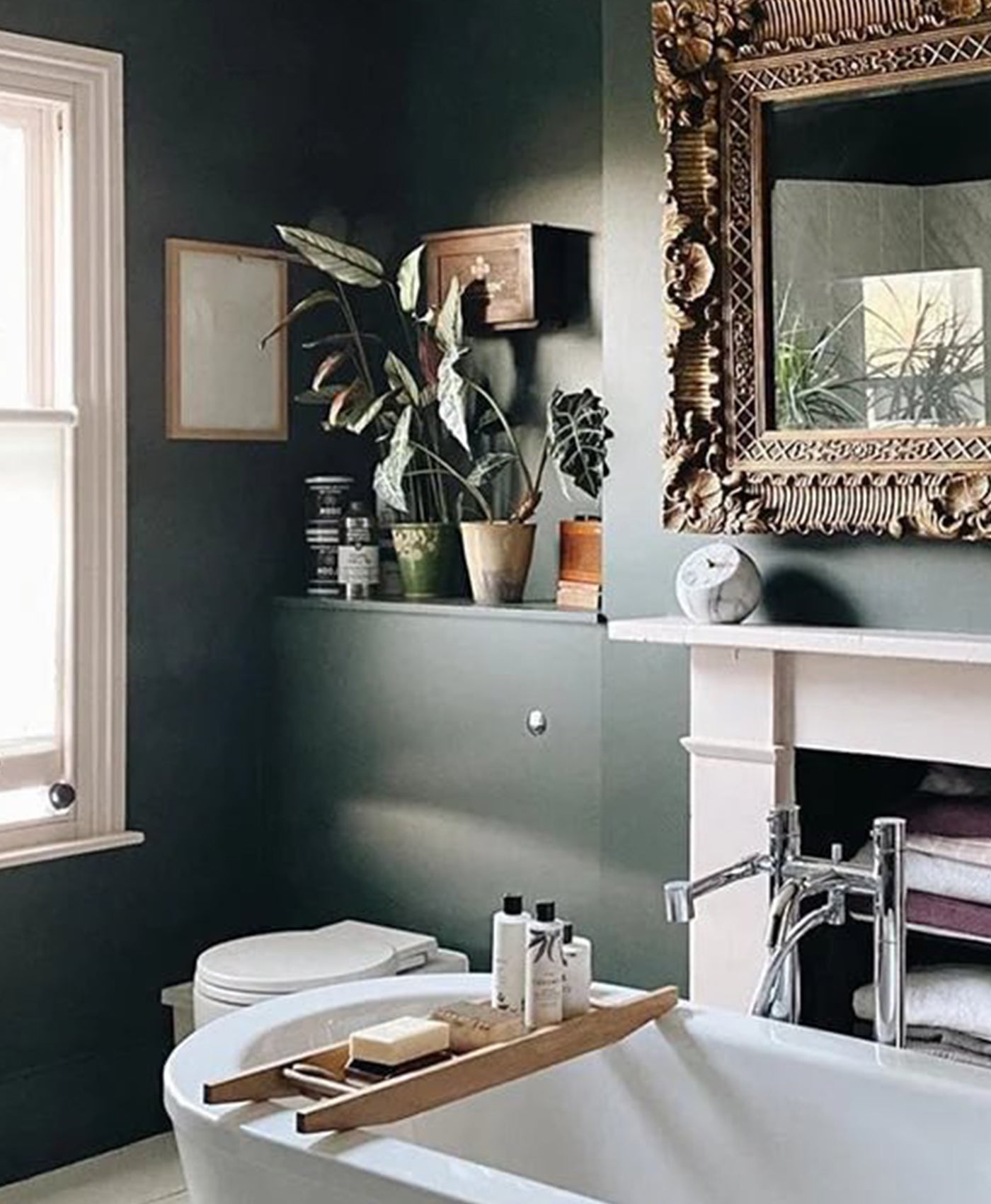 Bathroom with dark green walls, a bathtub, and decorative elements.