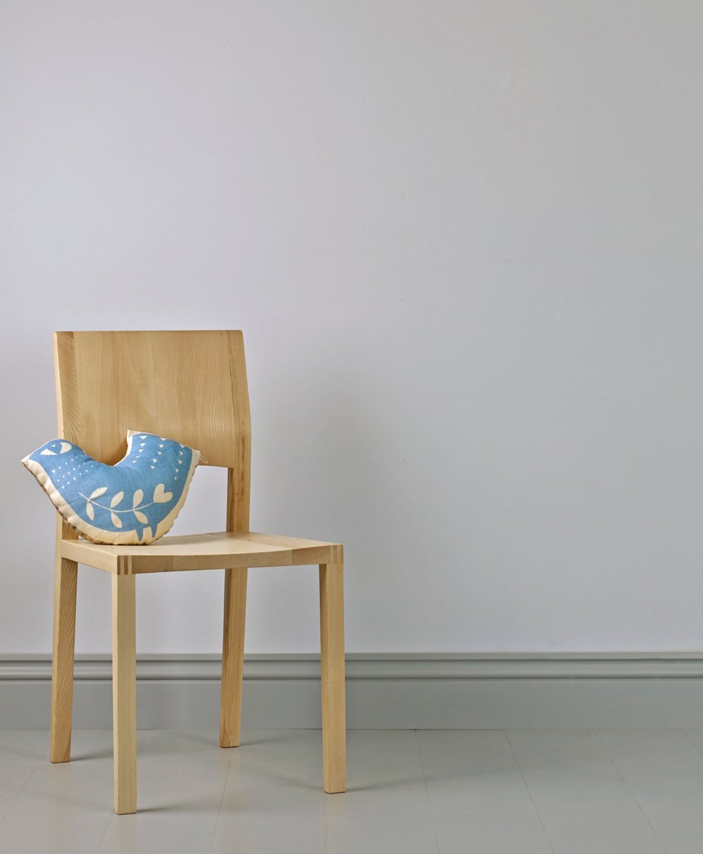 Wooden chair with a blue cushion on a off-white blue background