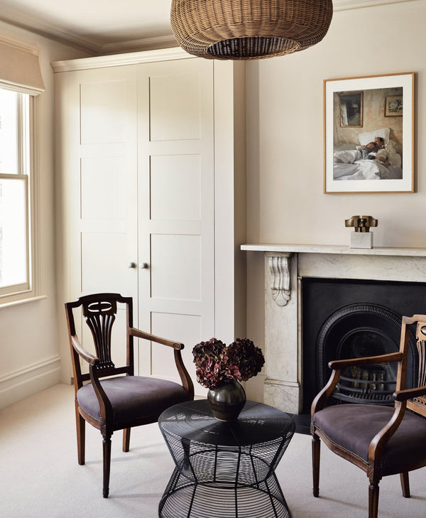 Warm off-white living room with two chairs, a small table, and a fireplace.