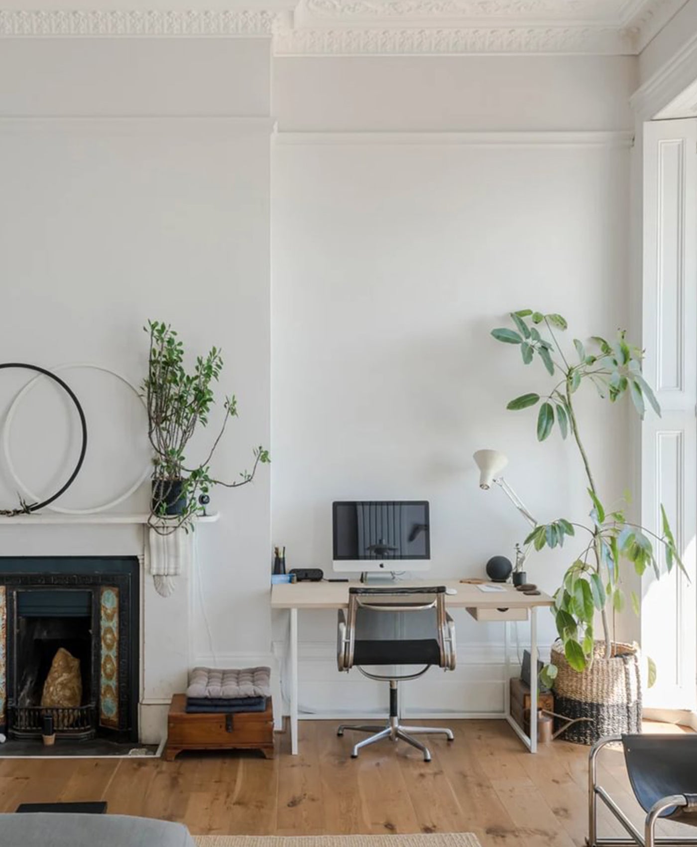 White home office interior with desk, chair, and plants in a well-lit room.