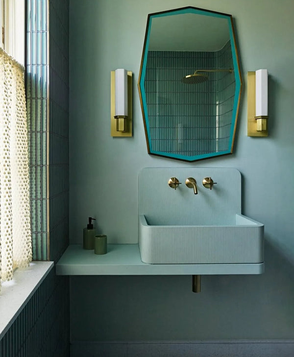 Green bathroom with teal sink, mirror, and wall sconces
