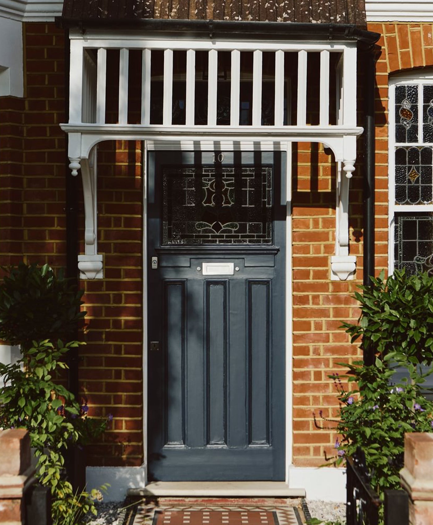 Navy blue door with decorative glass panels on a brick building