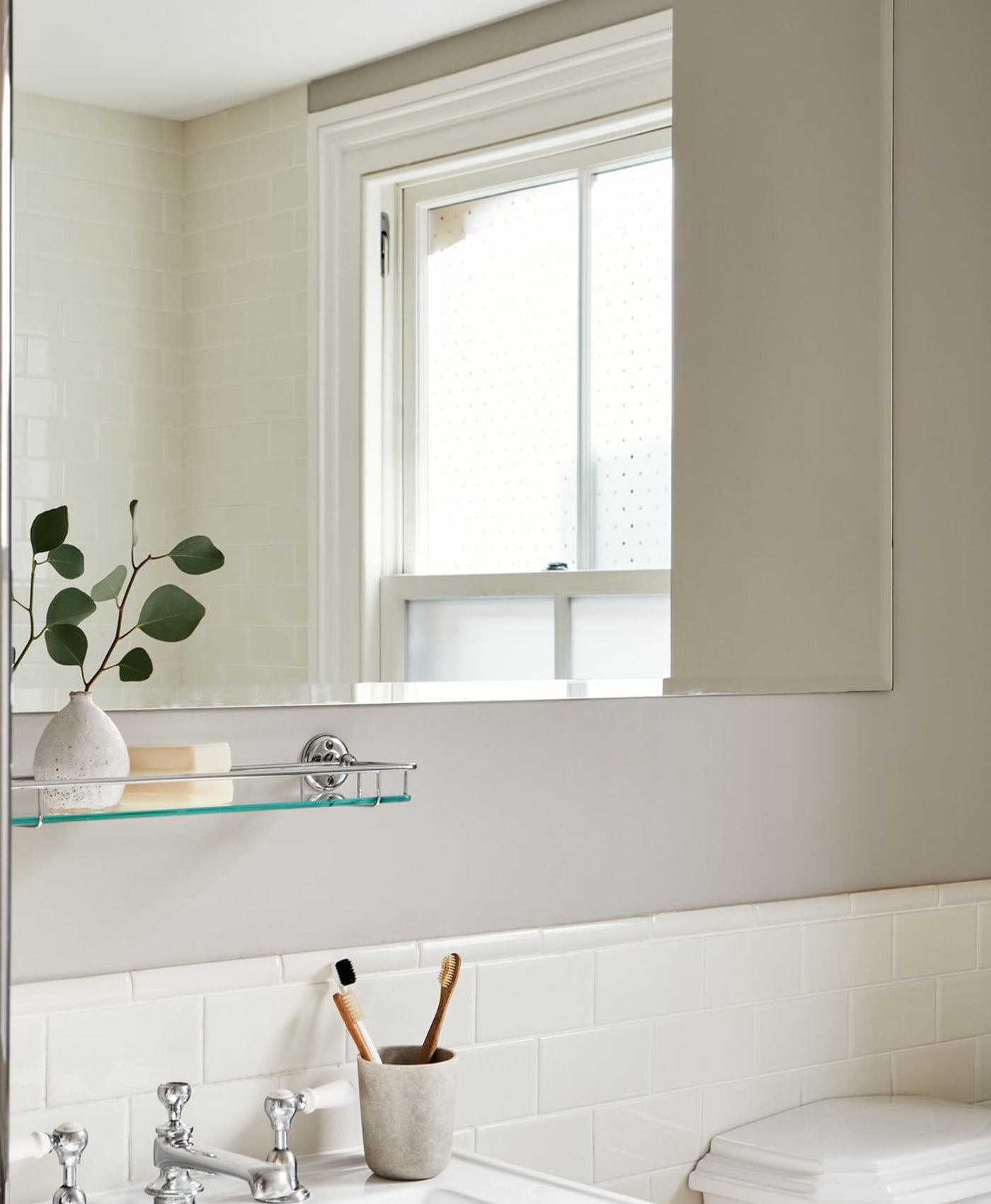 Bathroom interior with a window, mirror, and glass shelf.